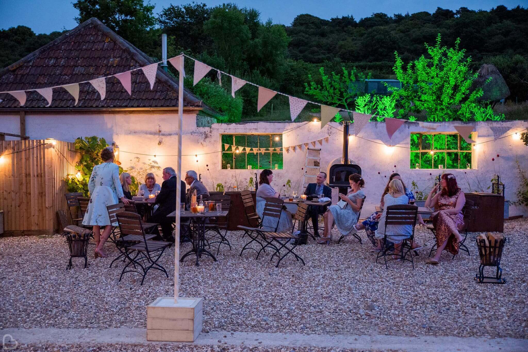 wedding guests sit and chat outside in river cottage hq wedding venue