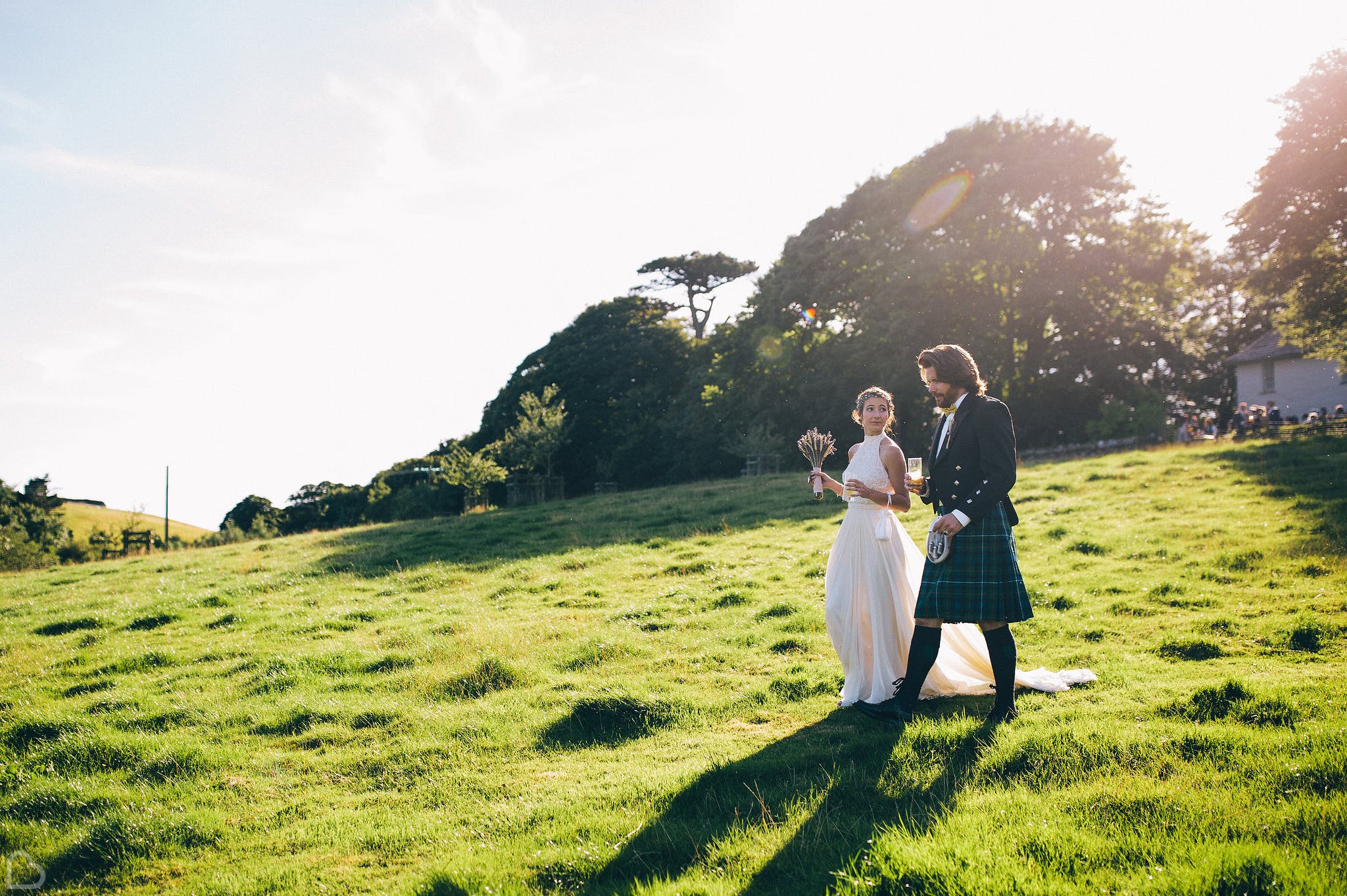 newlyweds walk down a green hill on a sunny day at trenderway farm