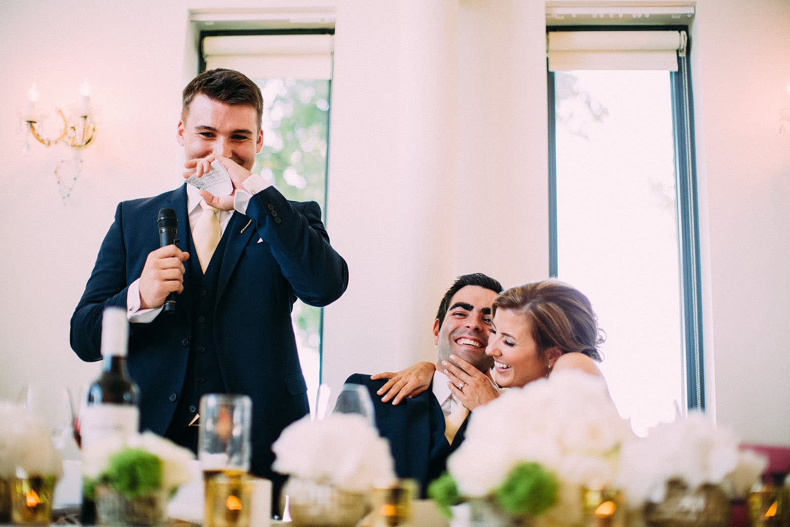 Bridebook.co.uk- best man giving speech as bride and groom hug