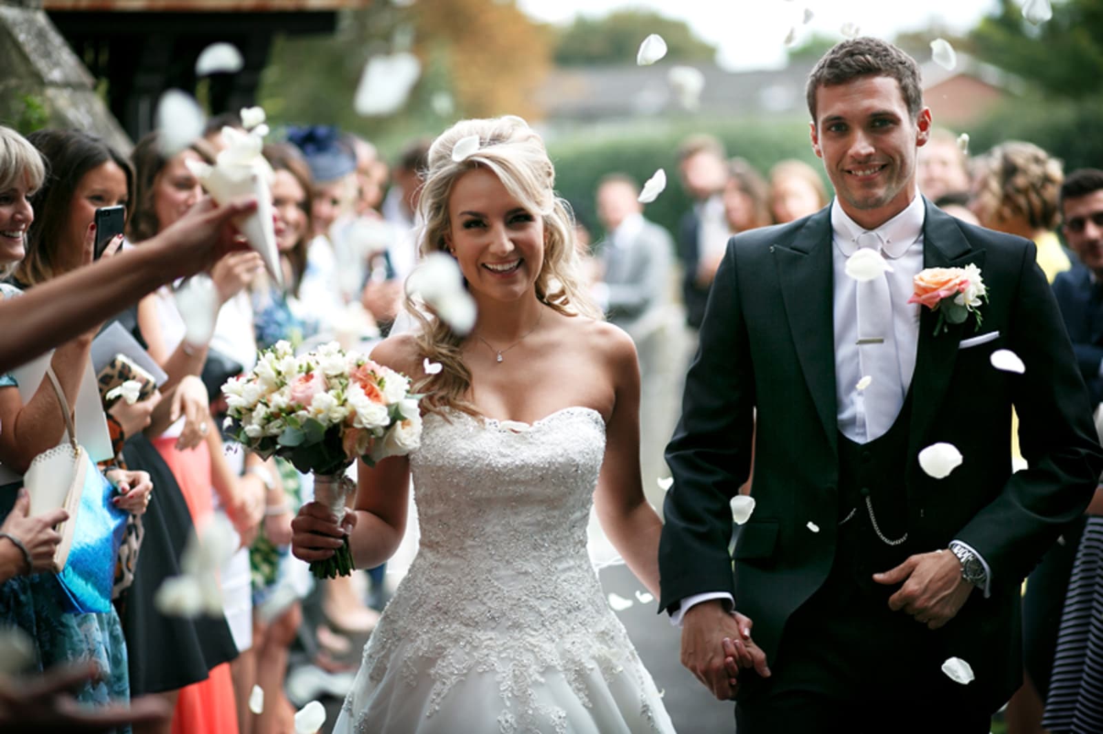 Bridebook.co.uk- bride and groom leave ceremony showered with confetti