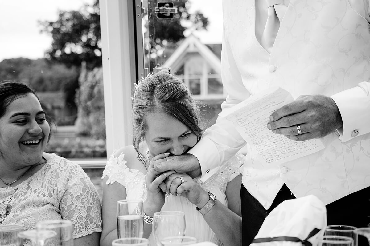 bride holds her dad's hand as he makes wedding speech