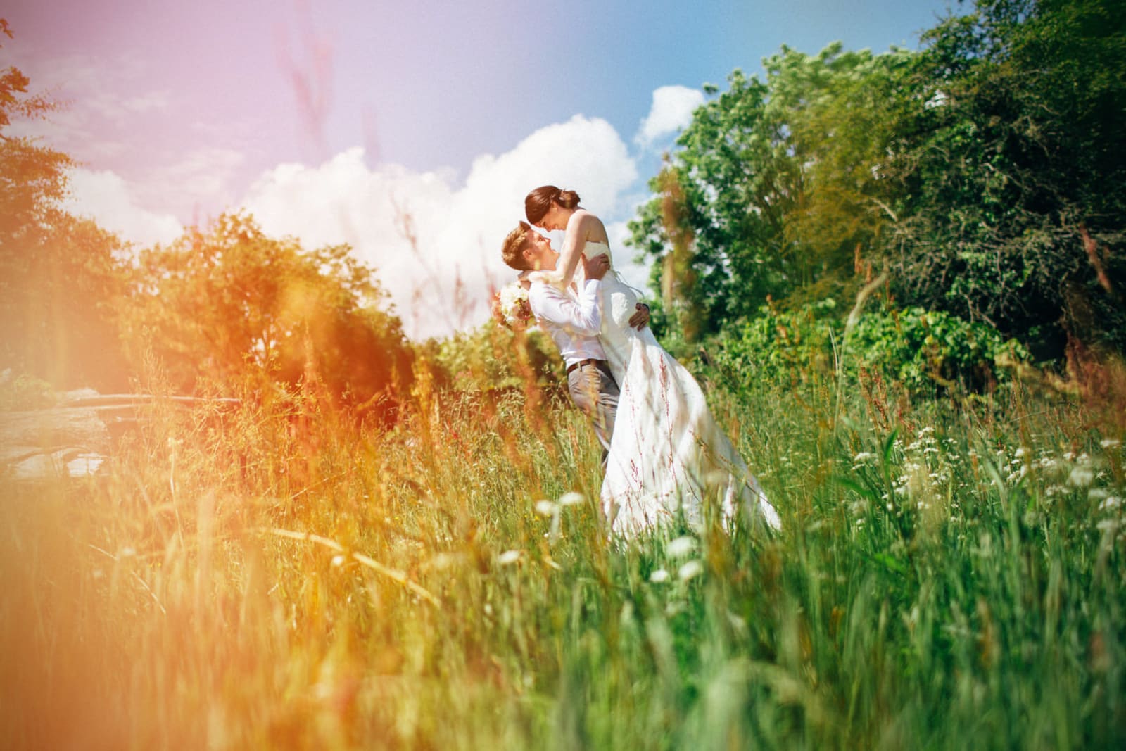 Bridebook.co.uk- groom lifting up bride in a field