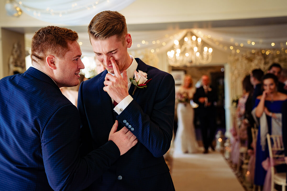 groom is comforted by his best man while he waits for the bride