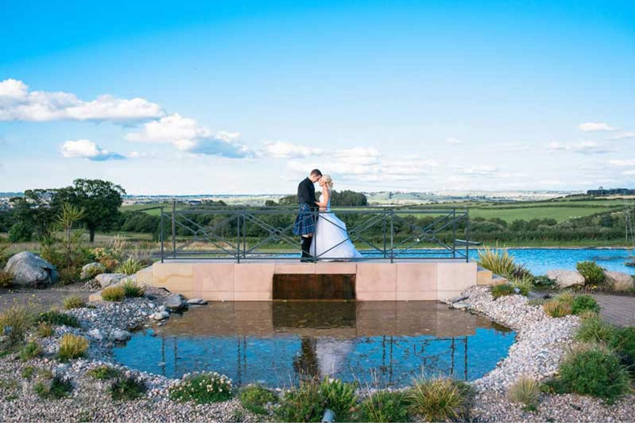 couple kisses on the bridge lake at radstone hotel