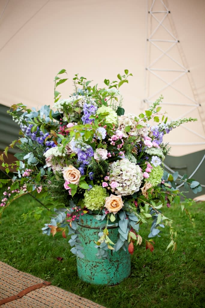 bridebook.co.uk pot of colourful flowers outside a tipi
