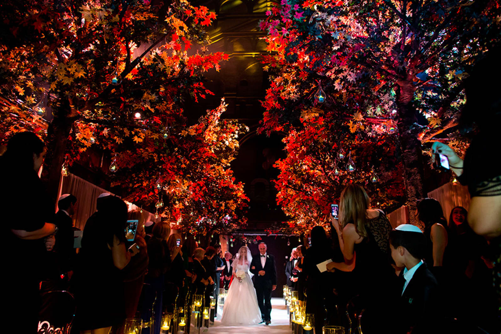 Bridebook.co.uk- bride walking up the aisle under red trees